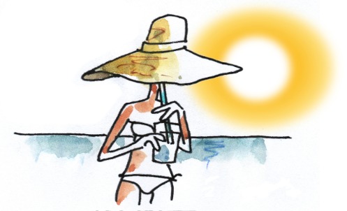 Frau mit Sonnenhut, trinkt am Strand aus einem Strohhalm
